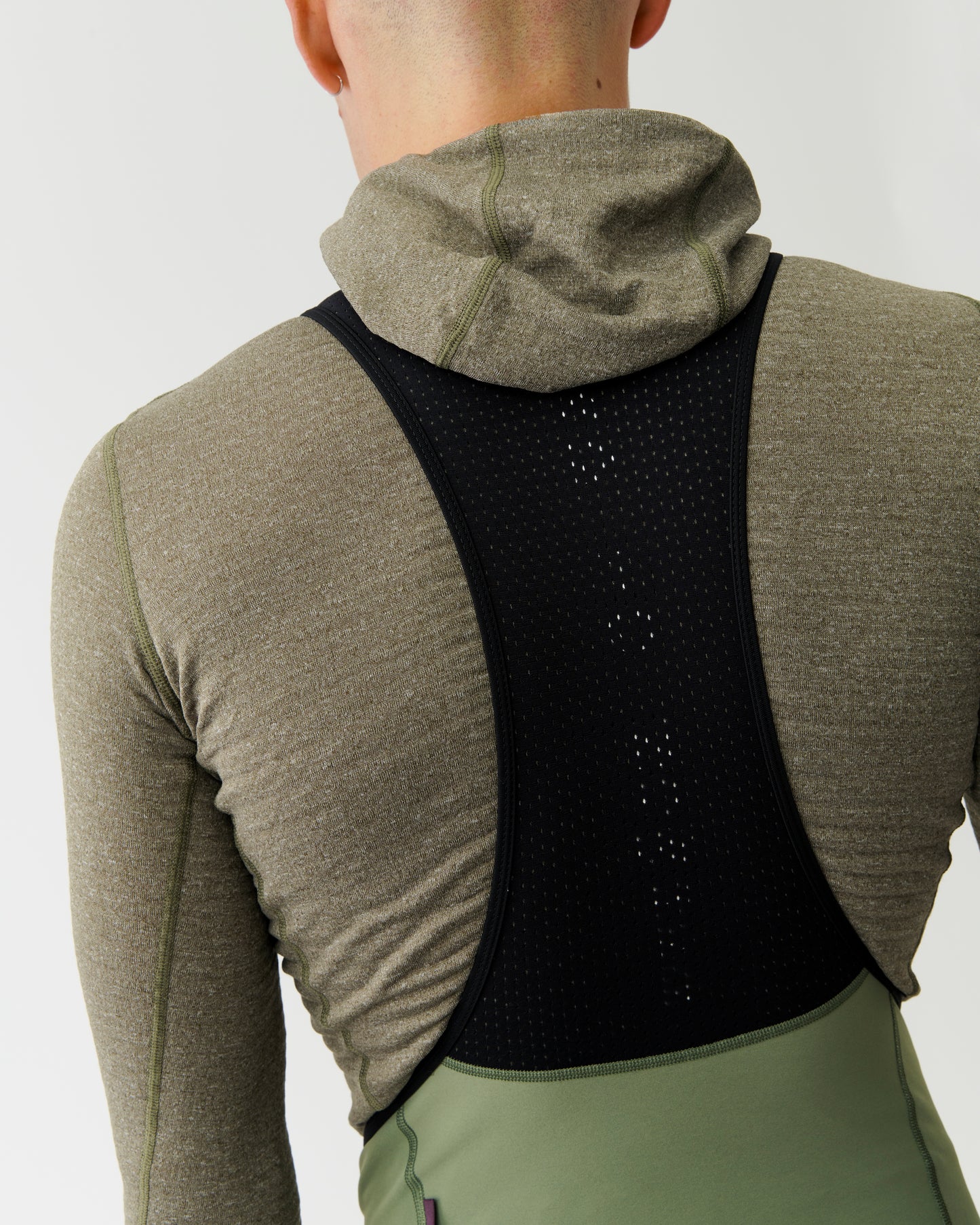Person wearing a black back brace over a green hoodie and pants on a white background