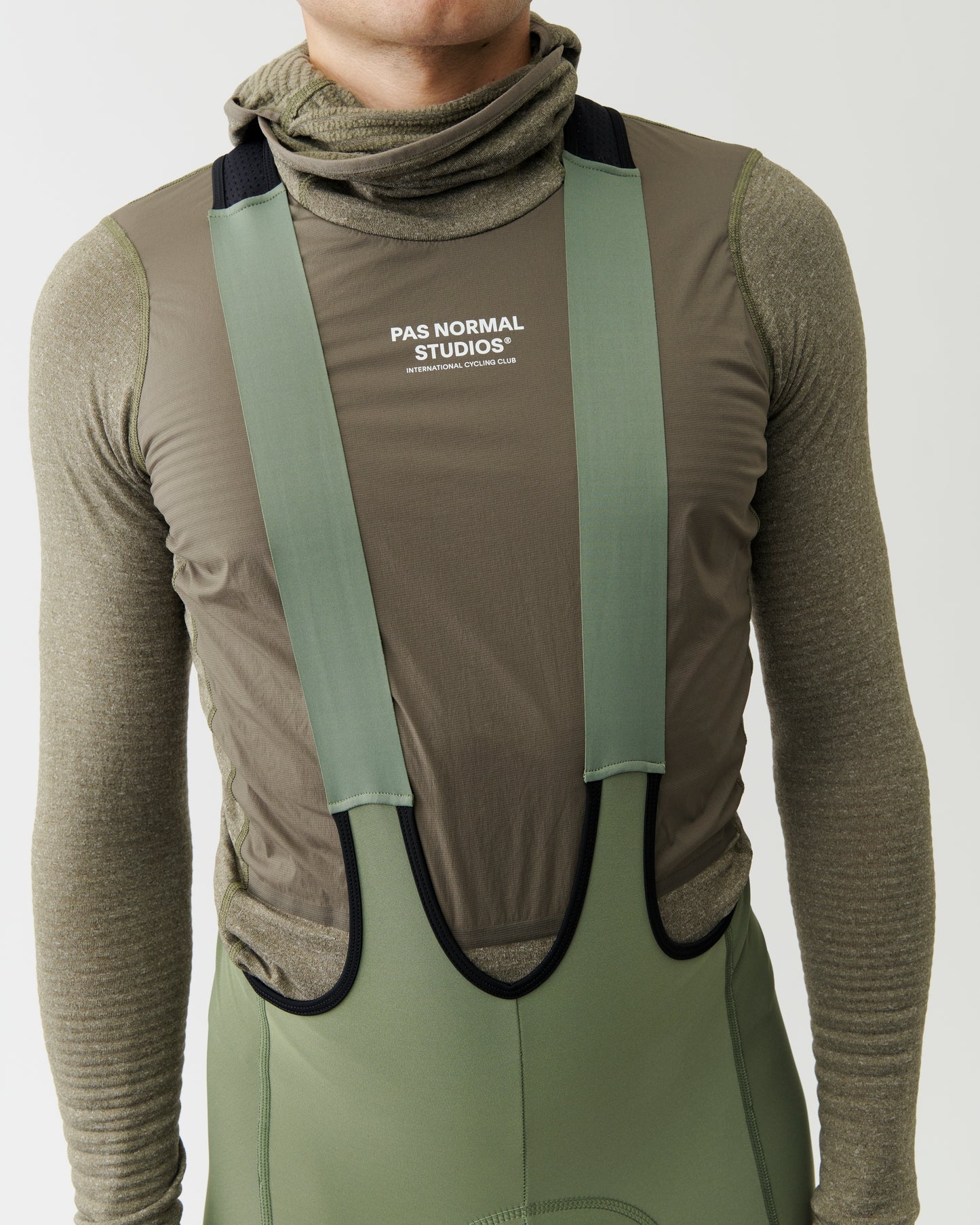 Person wearing a green and brown outfit with 'PAS NORMAL STUDIOS' branding on a plain background
