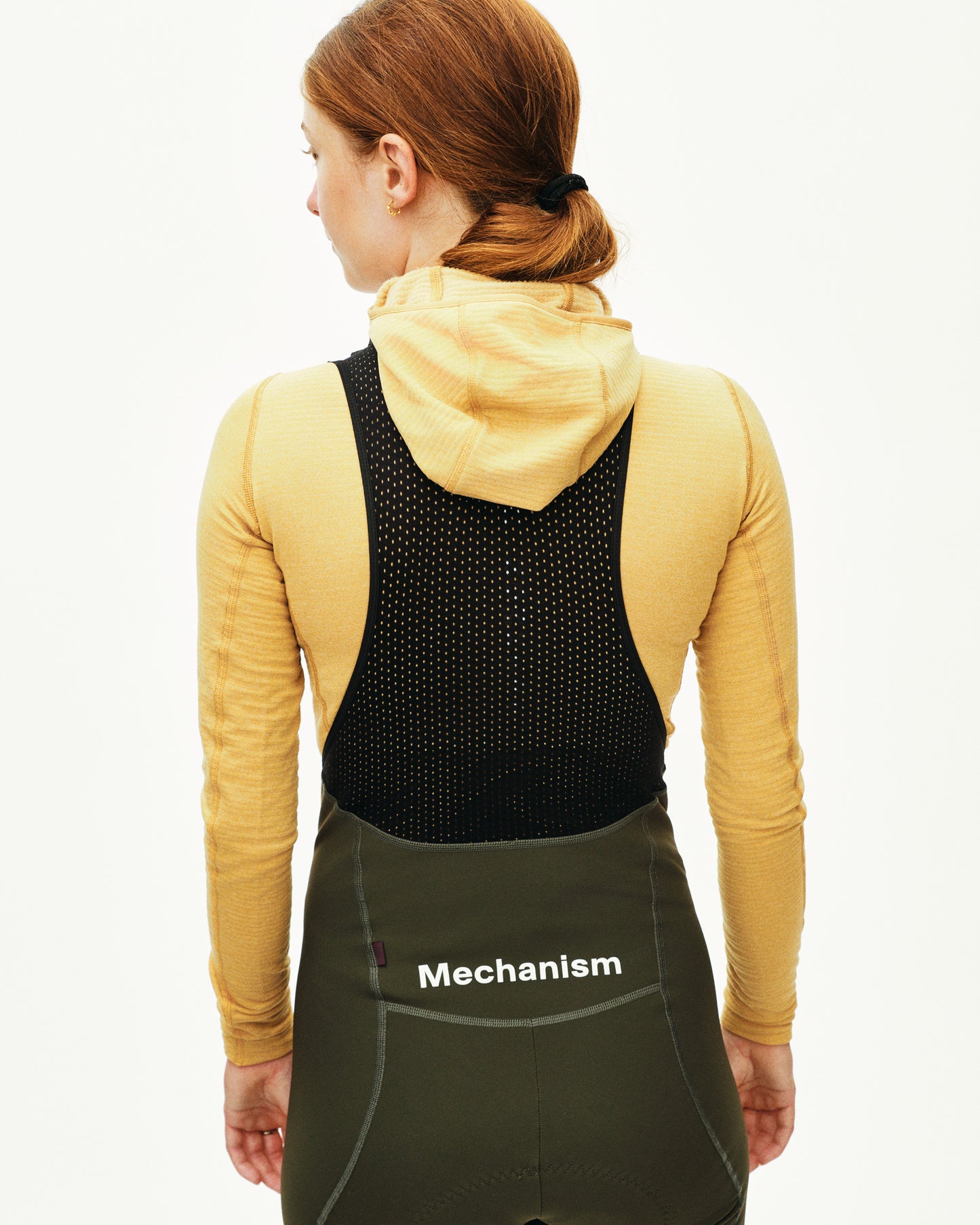 Person wearing a black back brace with 'Mechanism' branding on a white background