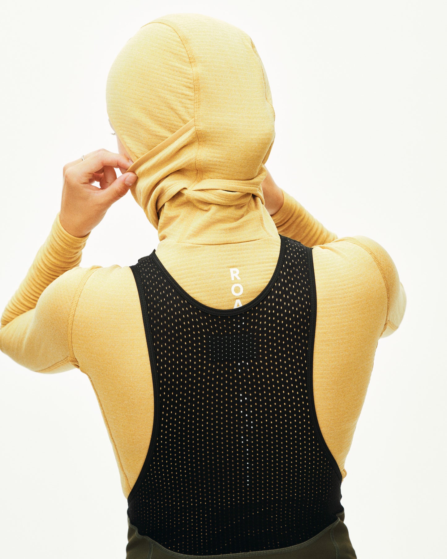 Person wearing a yellow headscarf and black sleeveless top with a brand logo.
