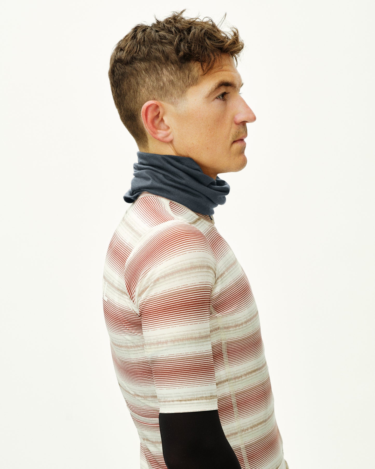 Man wearing a striped sweater and gray neck gaiter on a white background