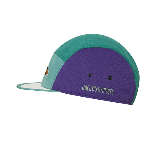 A cycling cap with a geometric pattern featuring shades of green and purple, and the text 'Café du Cycliste' on the front.