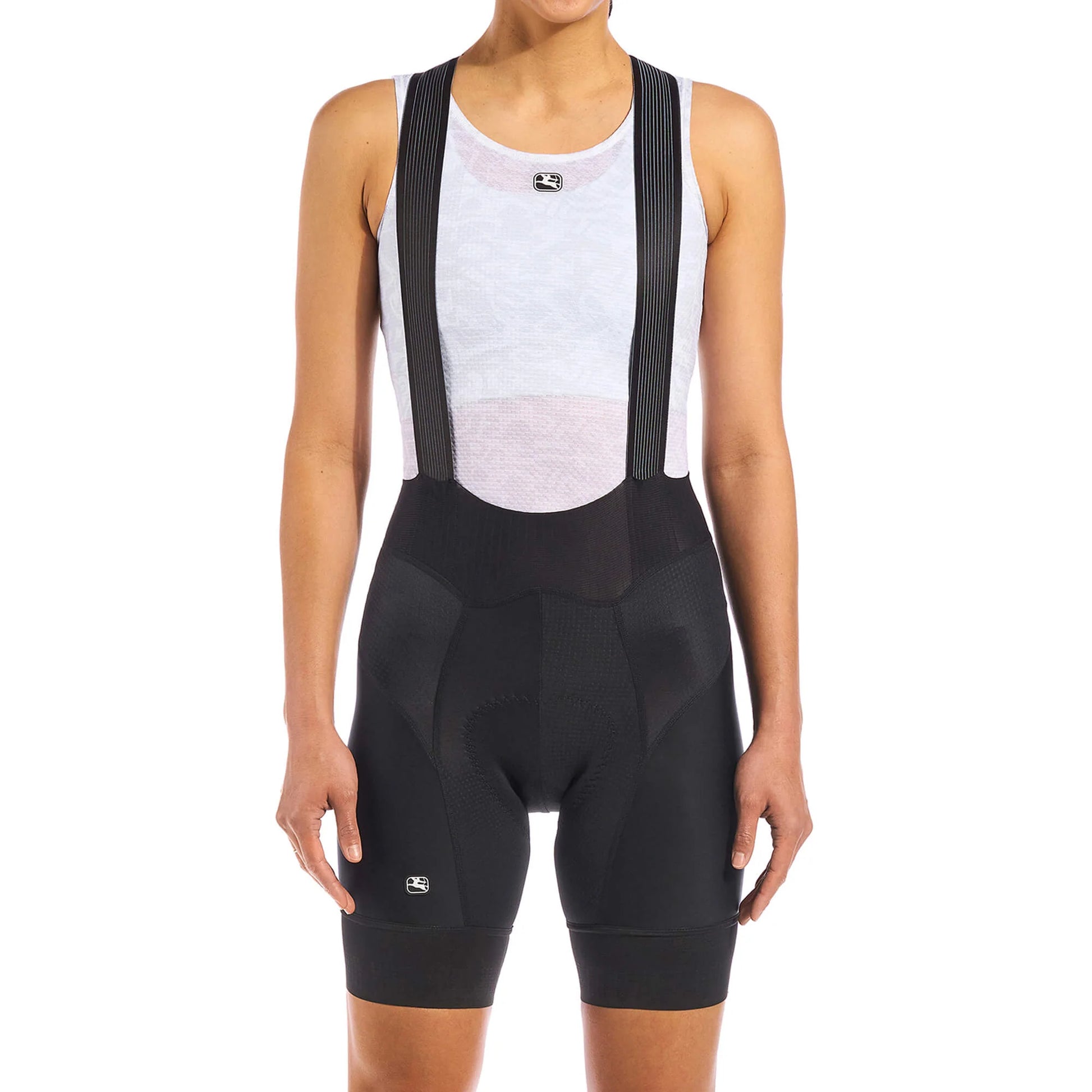 Person wearing black cycling bib shorts over a white tank top on a white background