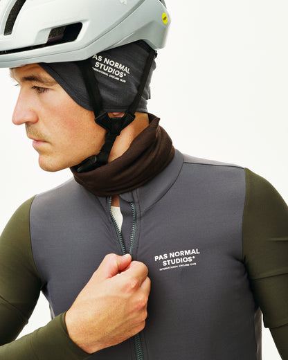 Person wearing a gray PAS NORMAL STUDIOS vest and helmet with a white background