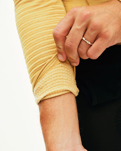 Close-up of a person wearing a yellow long-sleeve shirt with rolled-up sleeves.